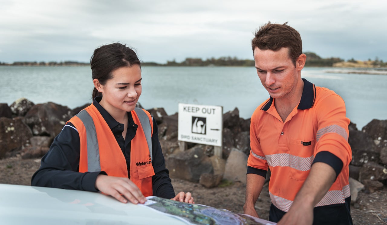 Watercare's Environmental Scientist Liam Templeton and his colleague Jen Harbour review maps of the bird sanctuaries in the background in Manukau Harbour.