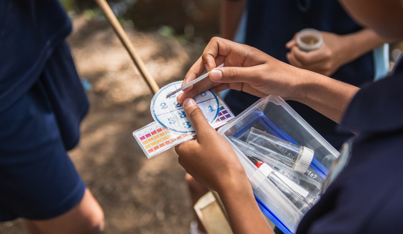 Northcross Intermediate School students test a water sample, using their Freshwater Detectives Kit colour reference charts and pH strips to measure the acidity of the water. Sample is taken from taken their local stream in Sherwood Reserve.