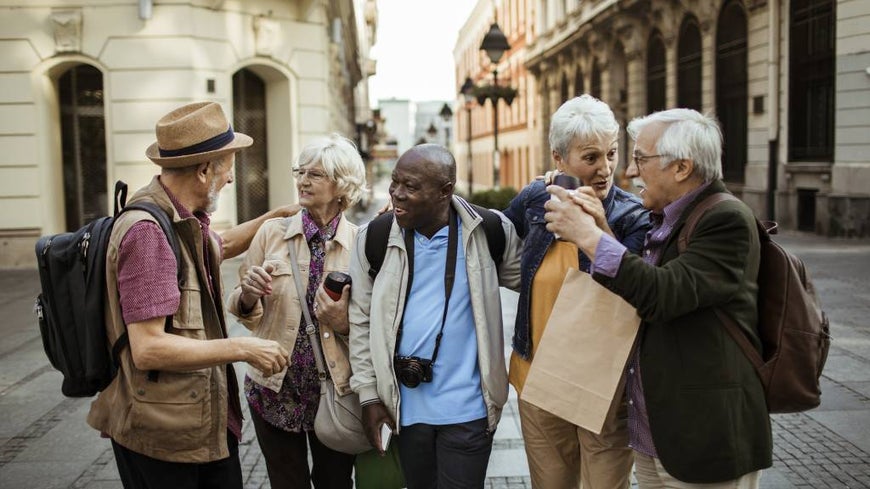 A group of senior travellers chat together in a scenic location.
