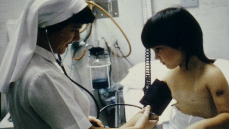 Sister Henry hold stethoscope up to young child 