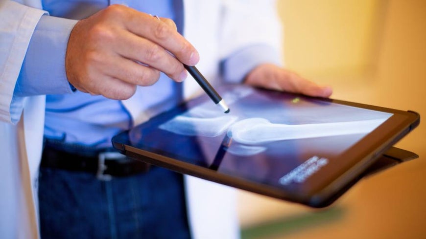 Medical professional looks at x-ray on a tablet