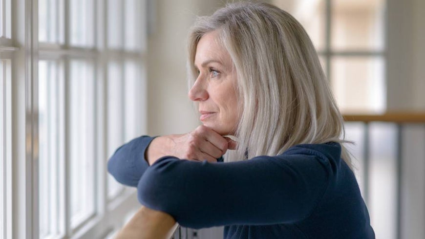 Senior woman looks out of the window. 