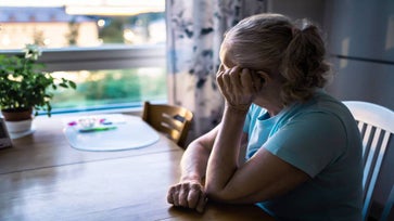 Lonely senior woman stares out her window.