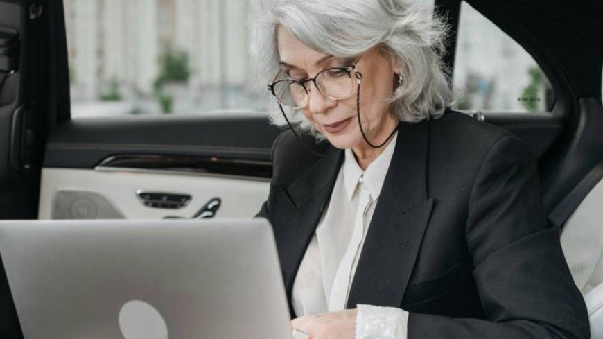 A senior woman checks her budget on a laptop