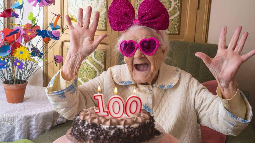woman celebrates 100th birthday with cake and decorations