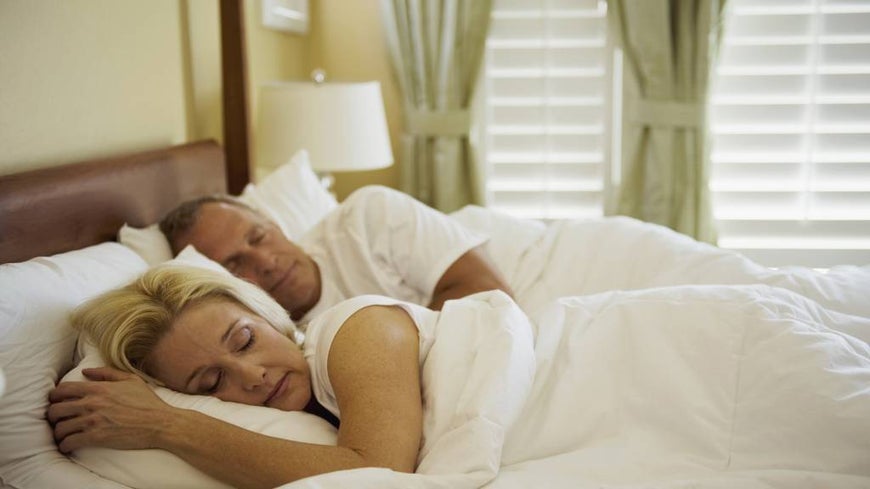 Mature couple sleeps in a double bed. 