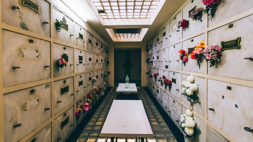Cemetery niches with flowers in a corridor.