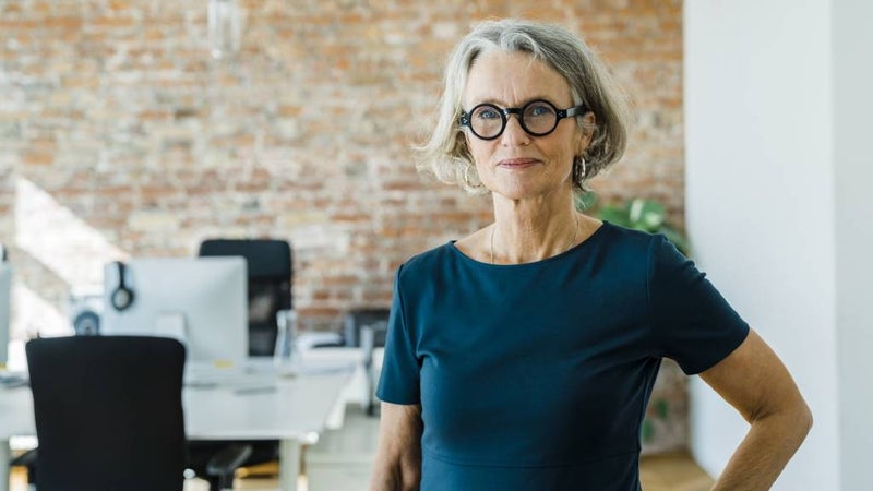 Mature woman stands in modern, contemporary office. 