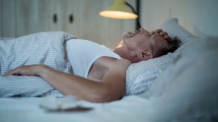 Senior man sleepless and frustrated in bed at night.