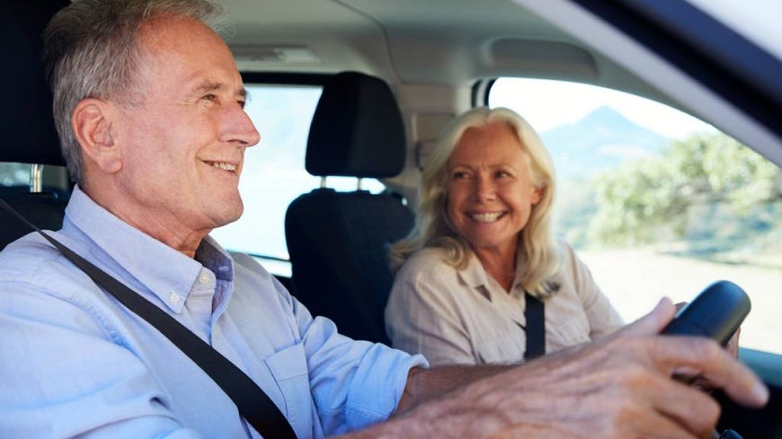 Senior couple drives in scenic location.