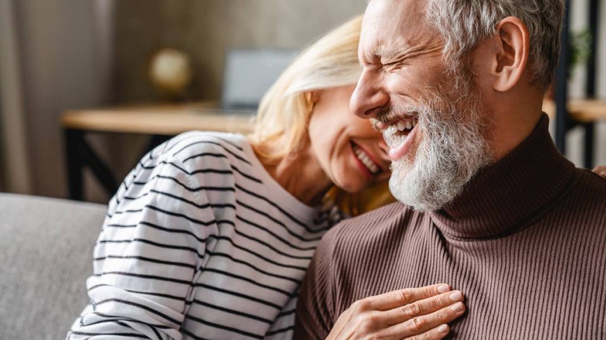 ALT: A fashionable senior couple embracing on a couch.