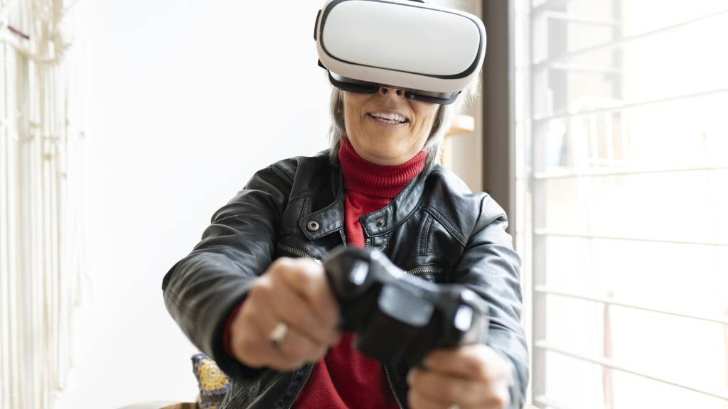 Senior woman uses virtual reality gaming system.