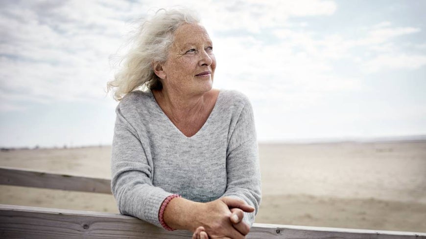 Senior woman standing on boardwalk on the beach