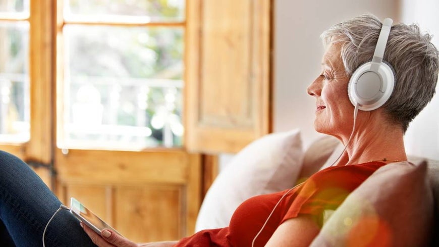 Older woman listens to music with headphones. 