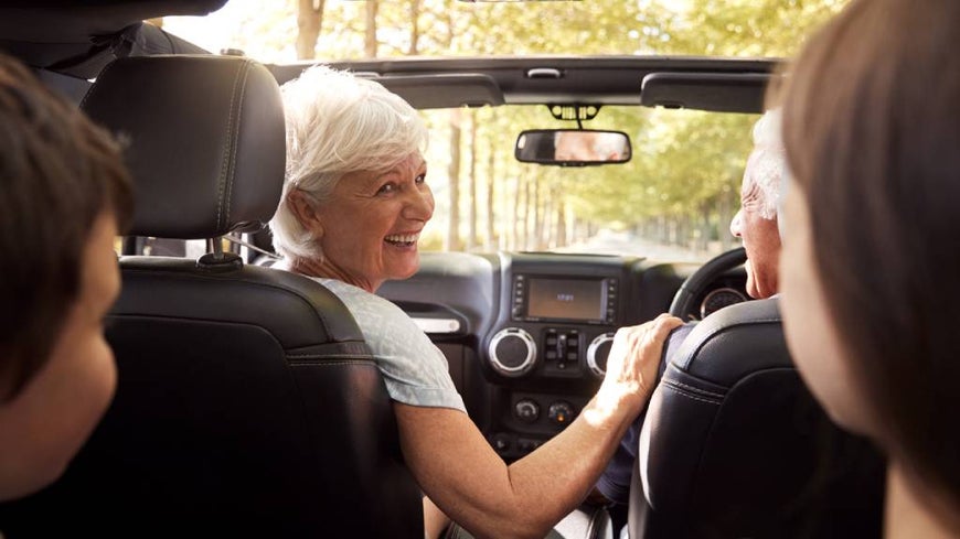 older couple driving with kids in the backseat