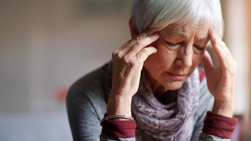 Older woman with short hair, experiencing a migraine.