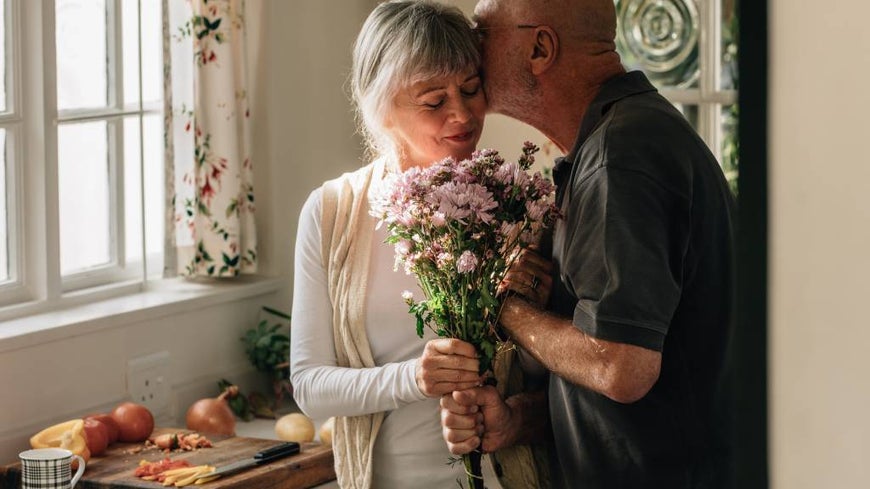 man kissing older woman in kitchen