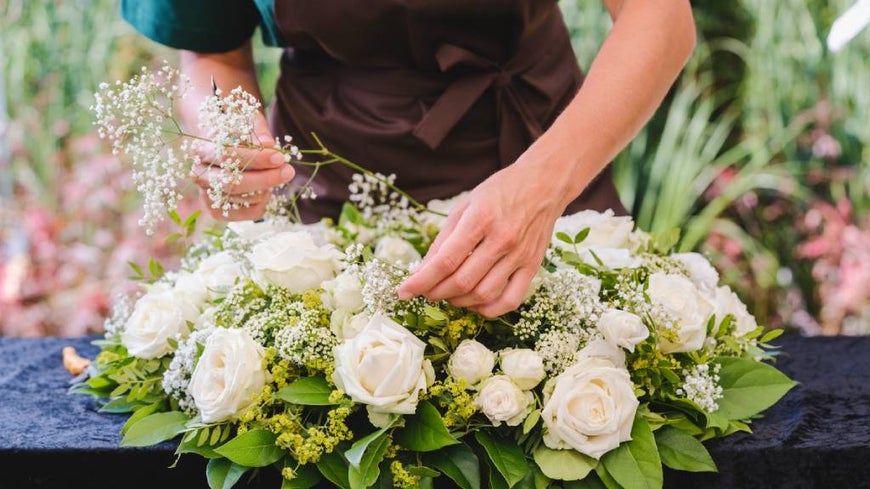 Florist decorates a white funeral wreath. 