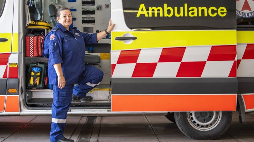Paramedic Karen Martin stands in front of an ambulance