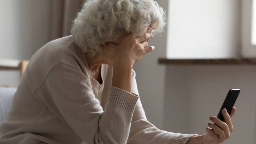 Older Australian woman looks at social media on smartphone.