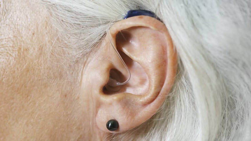 Hearing aid pictured in a senior woman’s ear. 