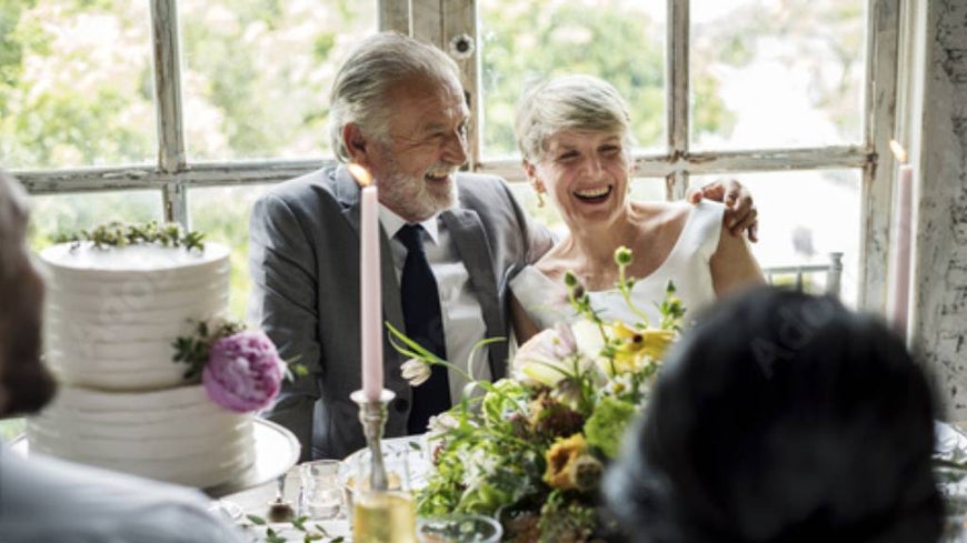 Senior couple at their wedding, surrounded by cake and decorations.