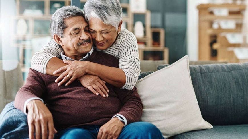 Older married couple embracing at home