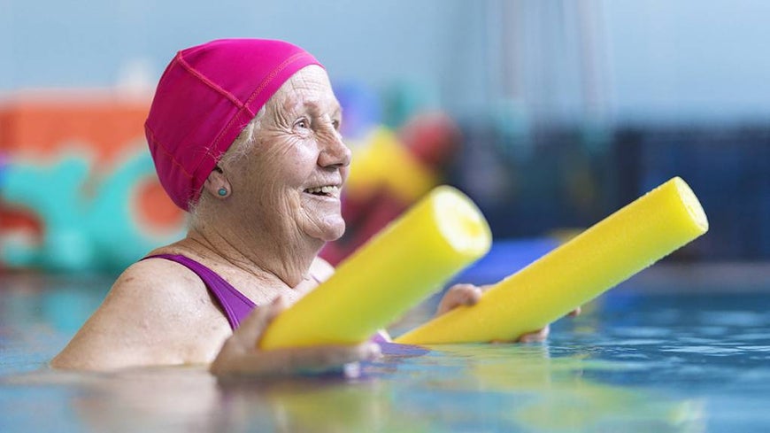 Senior woman in a swimming cap with a yellow pool noodle