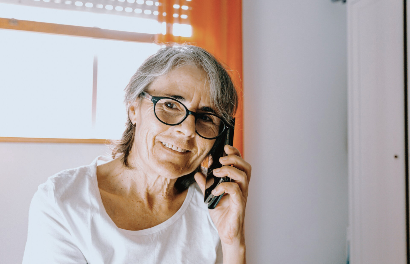A mid shot of a woman. She is talking on the phone - she is checking in on her friend's wellbeing. 