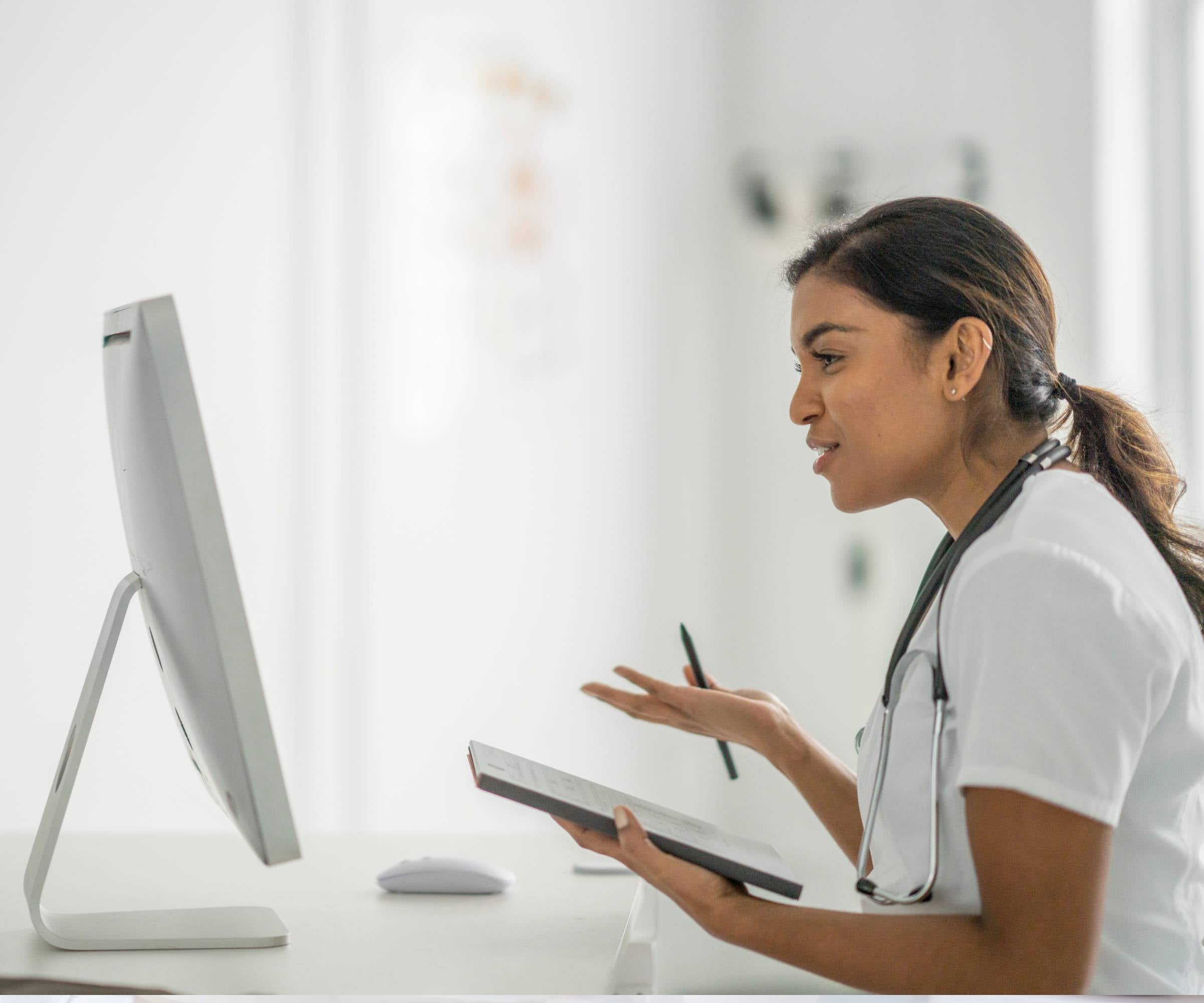 doctor sat at computer talking with notebook