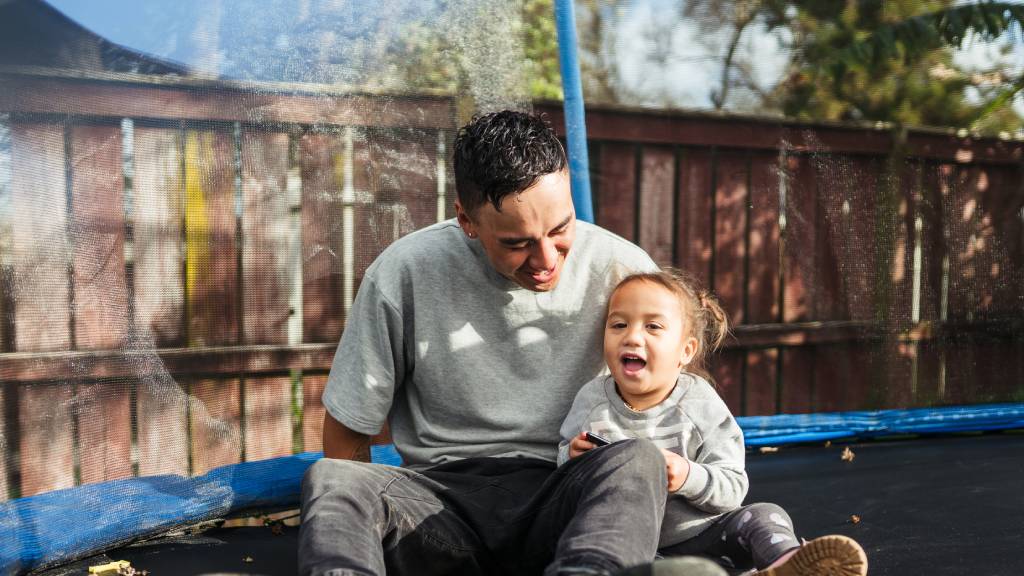 young Kiwi father playing with daughter on trampoline 