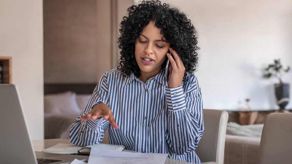 Woman talks on phone while looking at paperwork