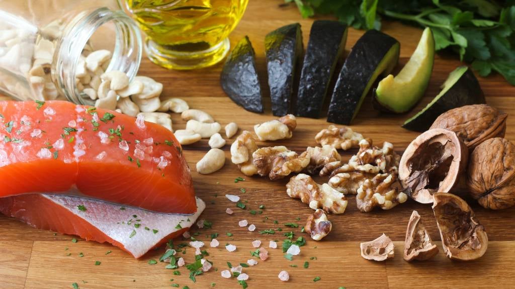 Omega-3 rich foods: Salmon, cashews, walnuts, sliced avocado and olive oil.