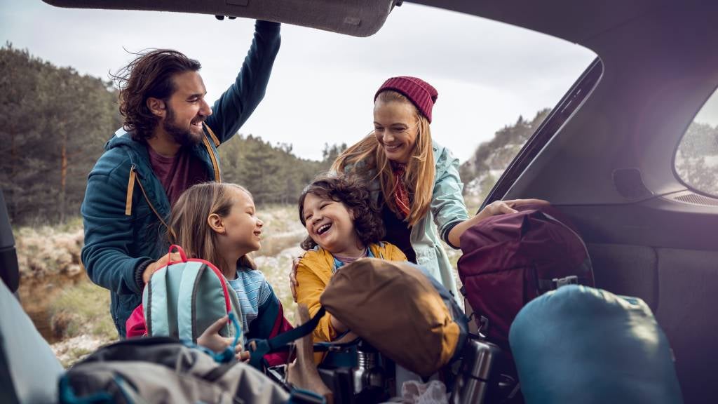 Young family getting camping supplies out of the car