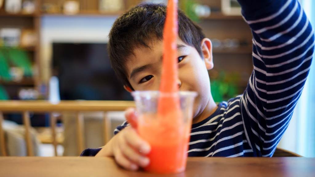 A young boy stretching out orange foam from a cup.