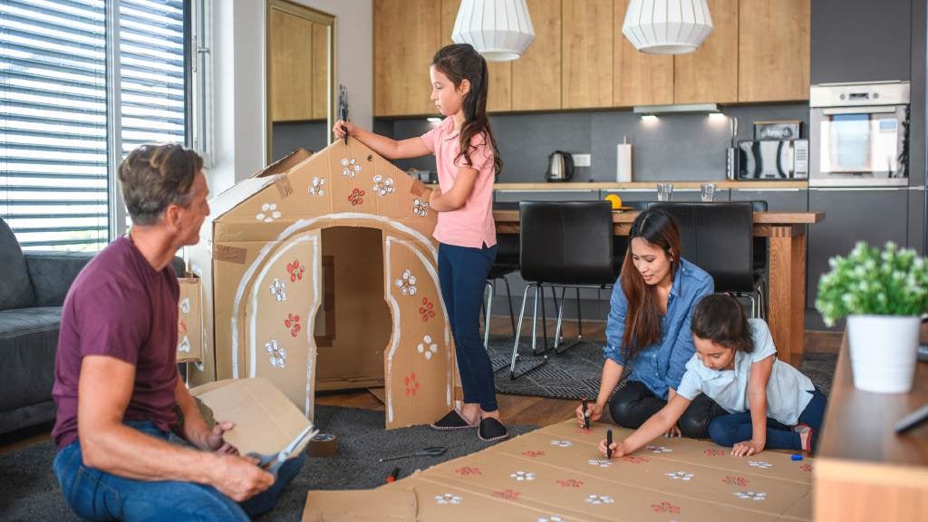 Family making a cubby house and painting cardboard.
