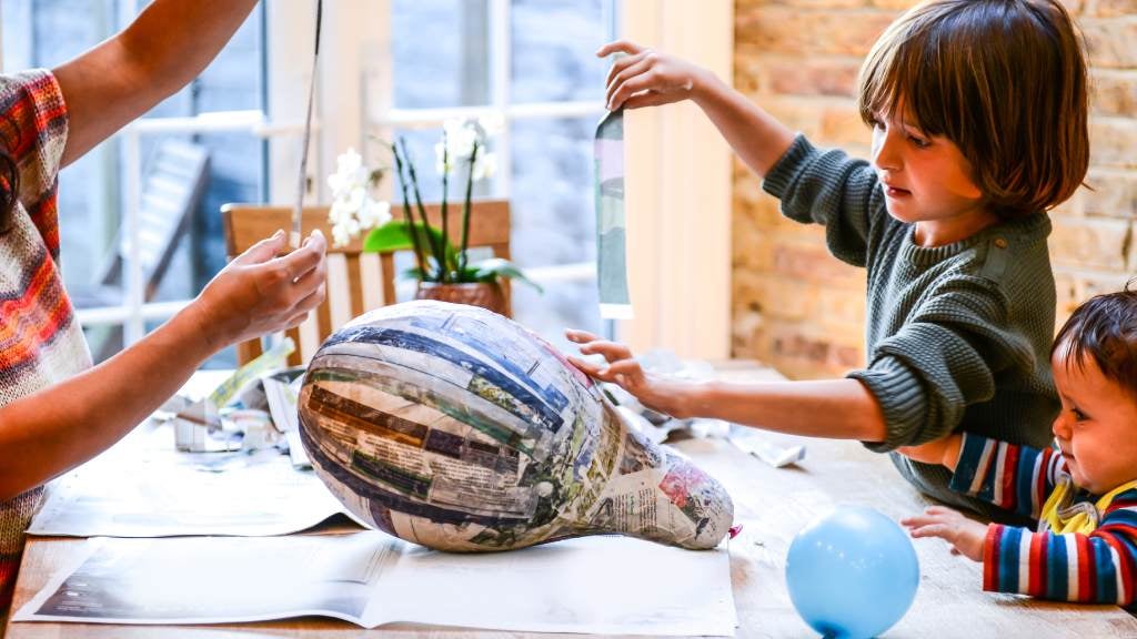 Kids doing paper mache on a balloon