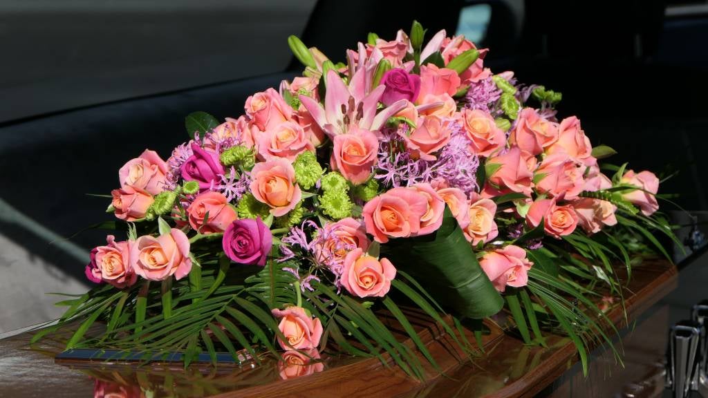 Colourful flowers resting on a coffin at a funeral