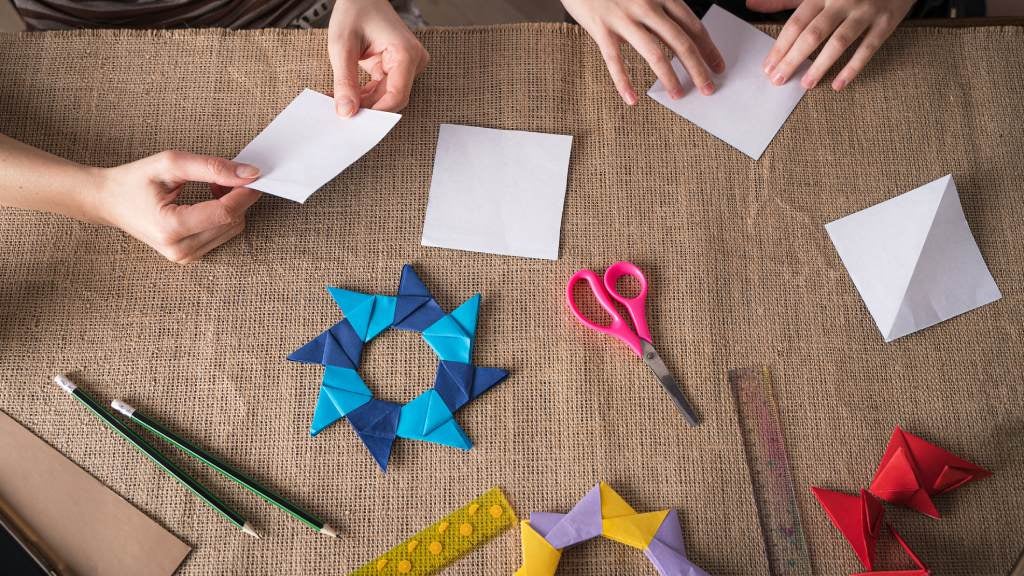 hands creating origami art and folding paper.