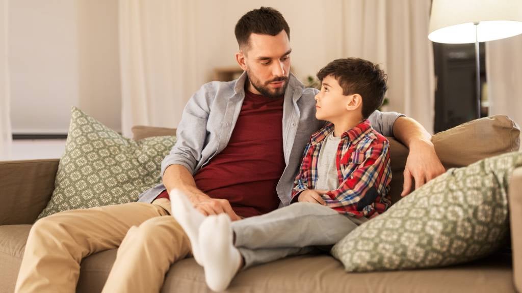 Father sits on lounge and has conversation with son