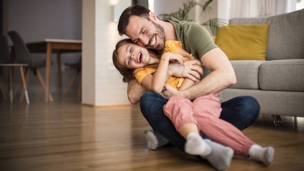 Father and daughter bonding, hugging playfully at home