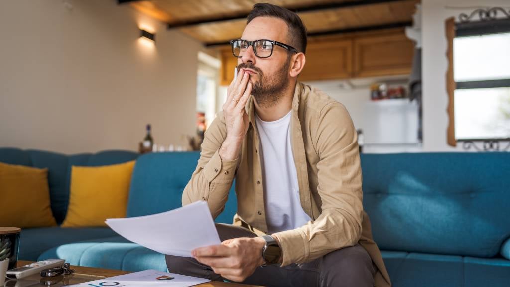 Man reviews paperwork at home sitting on lounge