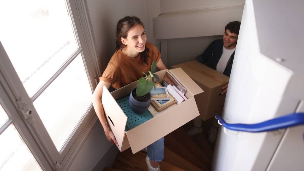 Couple walking up stairs with boxes moving into their new home.