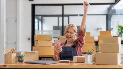 A happy small business owner fist pumps the air while on the phone