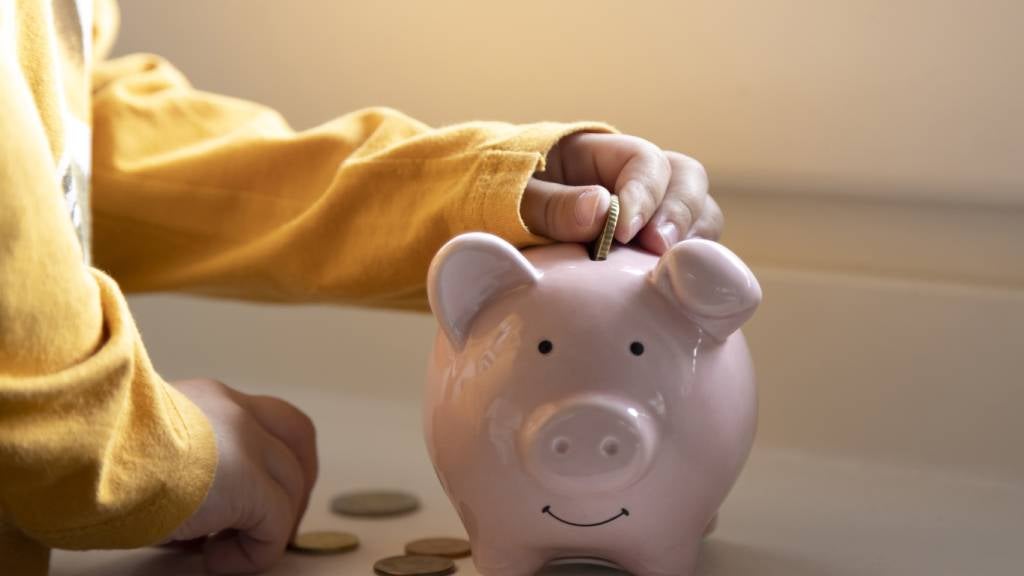 A person puts coins in a piggy bank