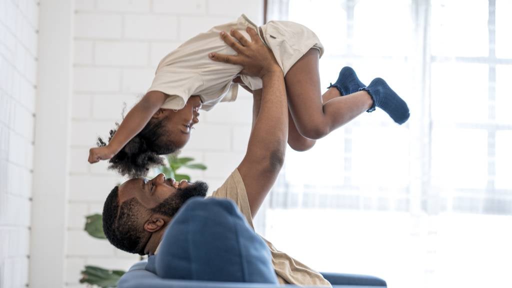 Father hold young daughter in the air at home