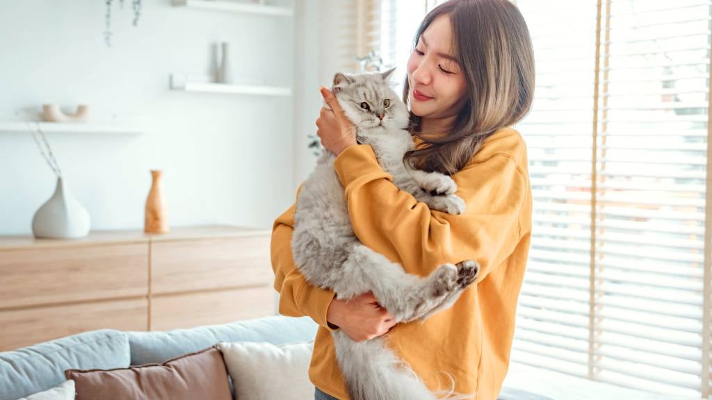 A young woman cuddles her fluffy cat