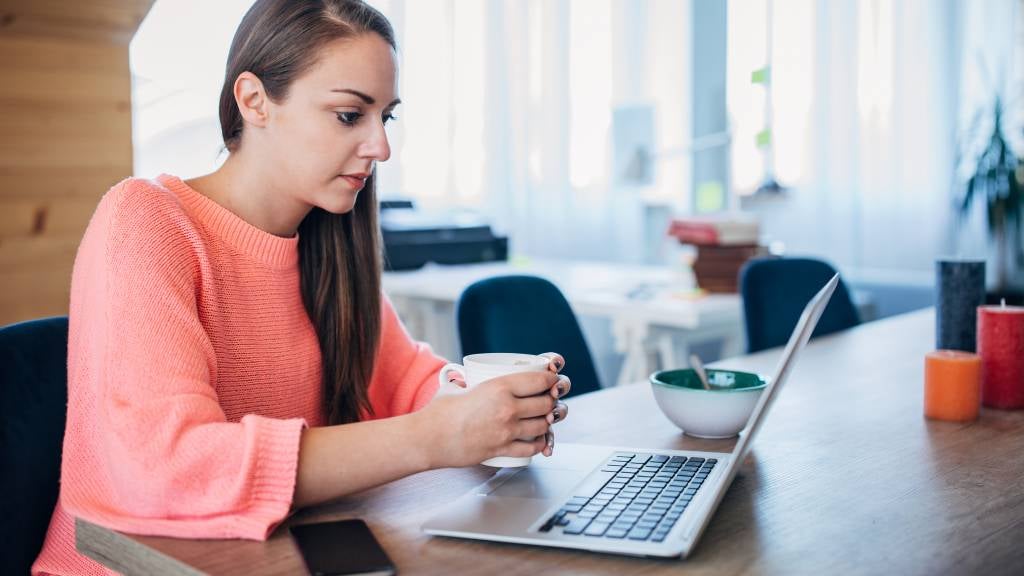 Young woman stares glumly at her laptop.