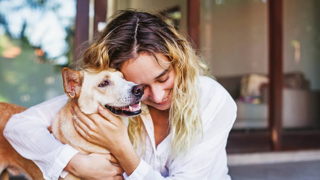 A smiling young woman hugs her dog