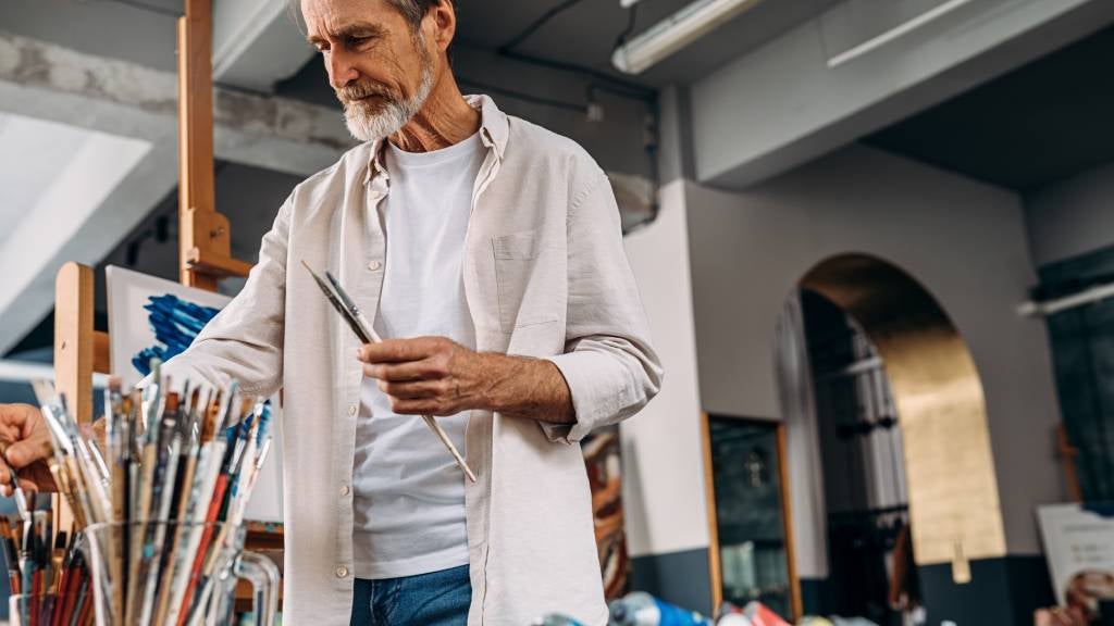 Senior man paints for grief therapy.